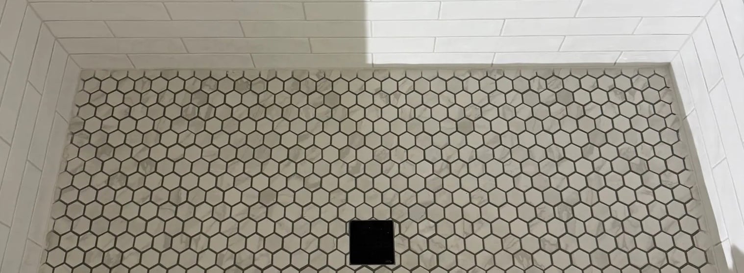 Finished shower with white subway walls, hex mosaic floor, and a square drain