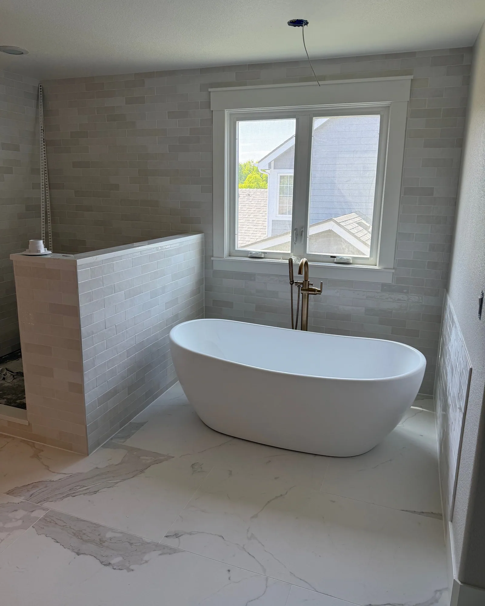 Freestanding tub with marble-look floor tile and subway tile walls in a Denver bathroom
