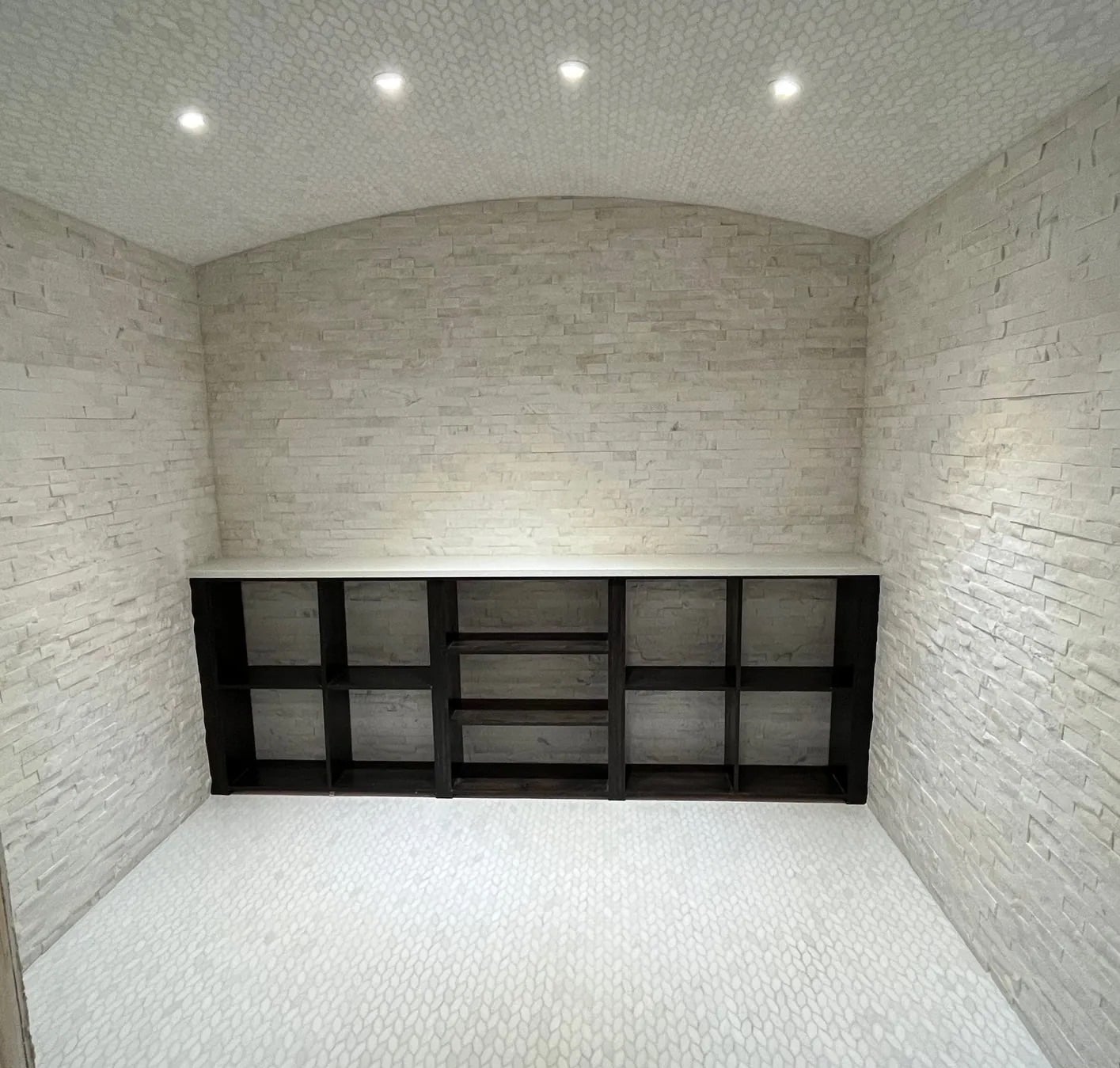 Tiled storage niche with stacked-stone walls and a matching mosaic floor and vaulted ceiling
