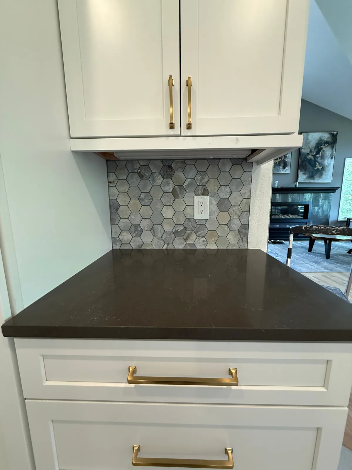 Hexagon stone kitchen backsplash between white shaker cabinets and a dark countertop