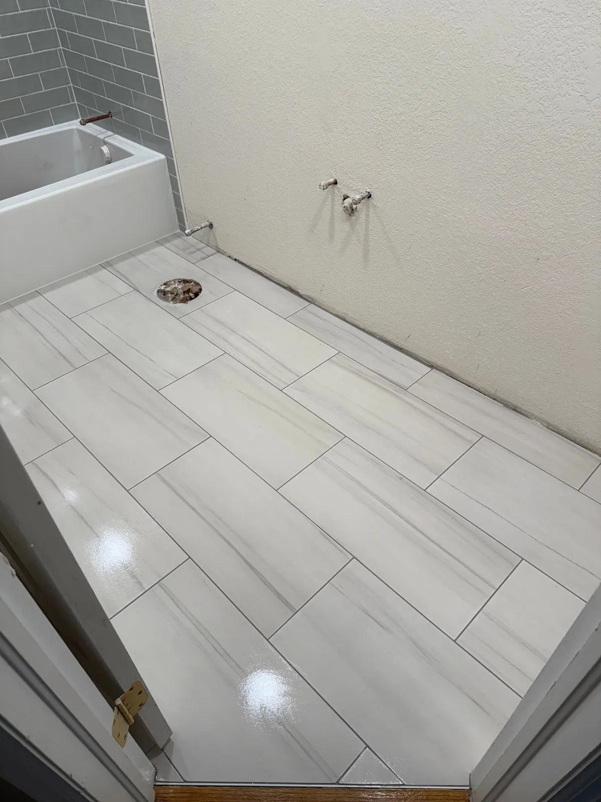Bathroom floor in large-format marble-look tile with a subway-tiled tub surround
