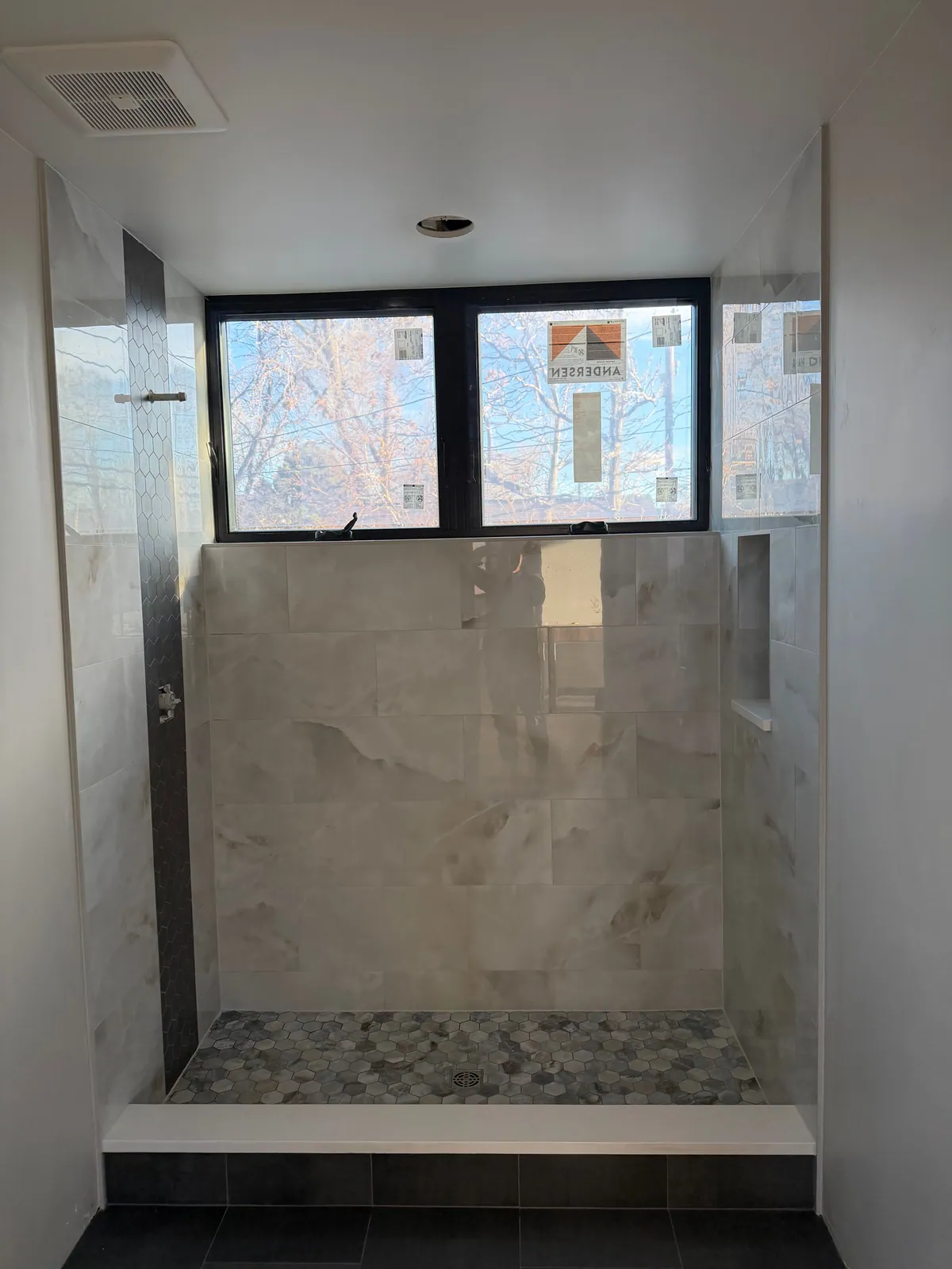 Walk-in shower with large marble-look wall tile, a hex accent strip, and a mosaic floor