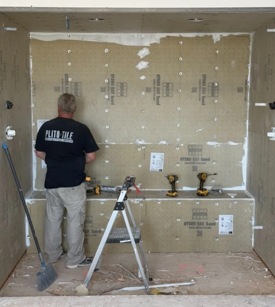Plito Tile installer waterproofing a shower enclosure with Hydro Ban board, a tiled bench, and tools on site
